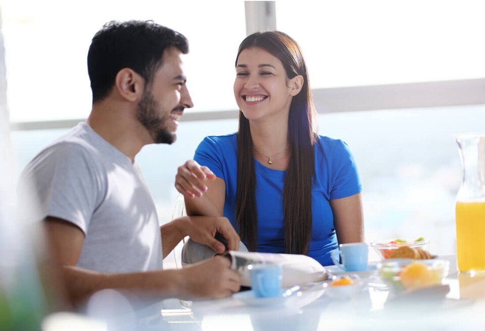 Pareja joven desayuna frente a ventana